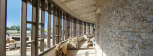 Construction view of curved interior hallway with stone bricks to the right and wall of windows to the left.