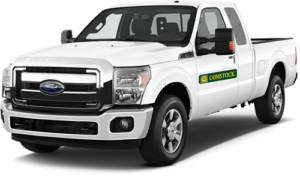 White Ford pickup truck with green Comstock logo vinyl decal on driver's side door.