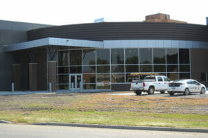 Exterior view of Bisek Hall entrance with curved wall of windows to the right with covered entryway to the left.