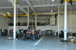 Large two-story garage with concrete floors and beige painted walls and exposed ceilings.