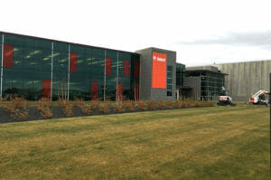 Exterior corner view of Bobcat building with wall of windows in dark gray and red with dark gray and red accents throughout.