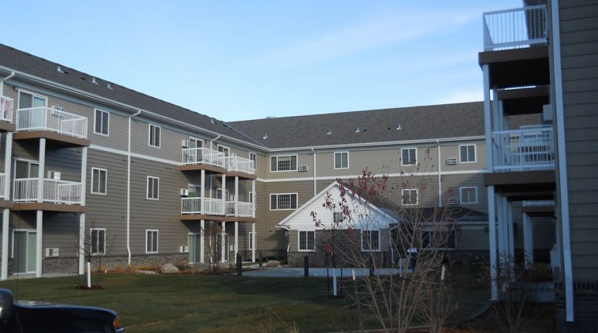 Courtyard view with green space beneath three-sides of a three-story residence building.