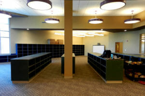 Large room with flat circular lights overhead, beige walls, and dark green cabinetry throughout.
