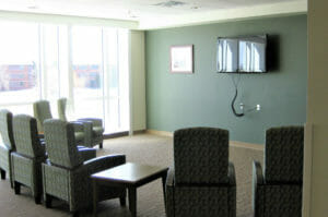 Lounge room with chairs and side tables looking toward accent green wall with big-screen tv.