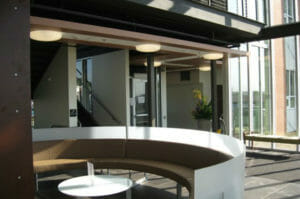 Semi-circle couch with white backrest and brown seat cushions around small white coffee table.
