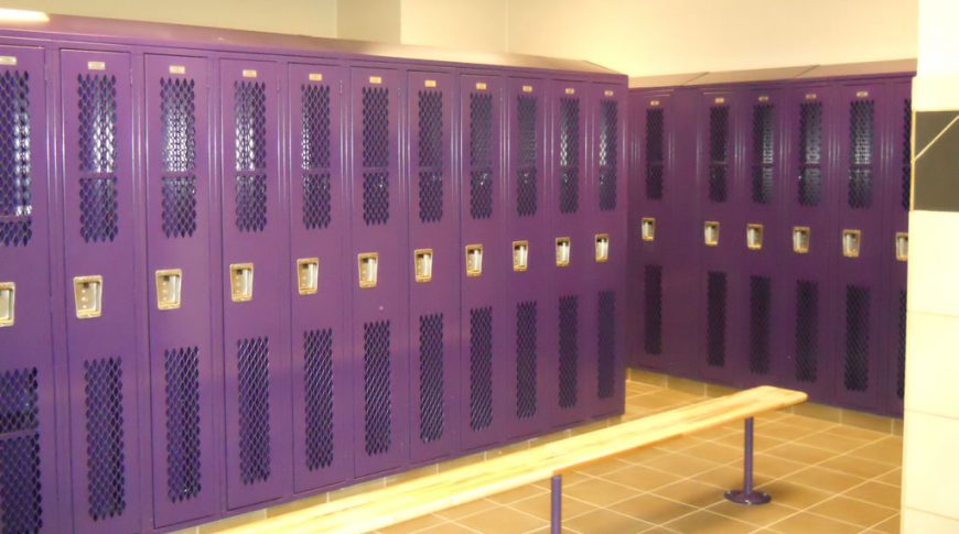 Purple locker room at New Town High School with wooden bench seat in foreground.