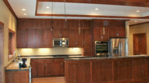 Cherry-wood kitchen cabinetry with stainless steel appliances and beige walls.