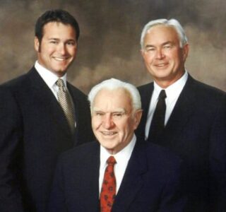 Three generations of Comstock men with black suites, white-collared shirts and ties on brown backdrop