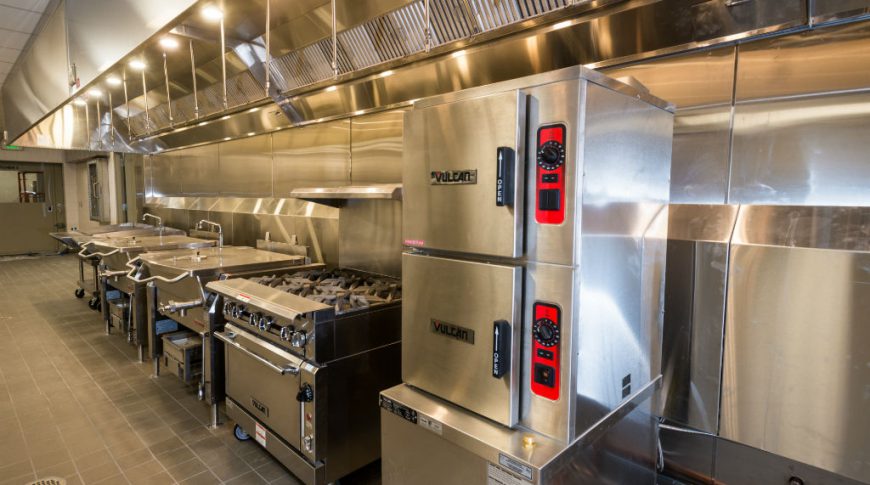 Burleigh Morton Detention CenterP-Int1-1024x680-Government Construction Industrial kitchen with stainless steel appliances all under large long vent hood.