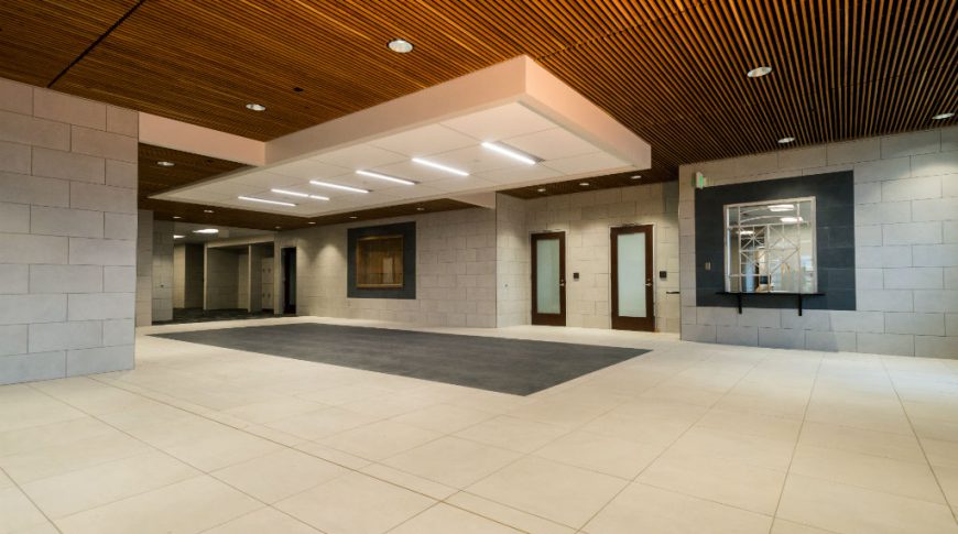 Burleigh Morton Detention Center-P-Int2-1024x680-Government Construction Large open building entryway with concrete block walls, light beige tiled floors, and overhead wooden slats.