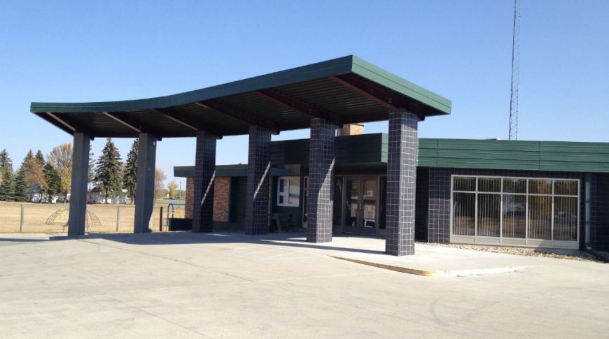 Cavalier County Memorial Hospital-Ext1-1024x680-Healthcare Construction Black-tiled and red brick exterior of building with drive up-green-covered awning.