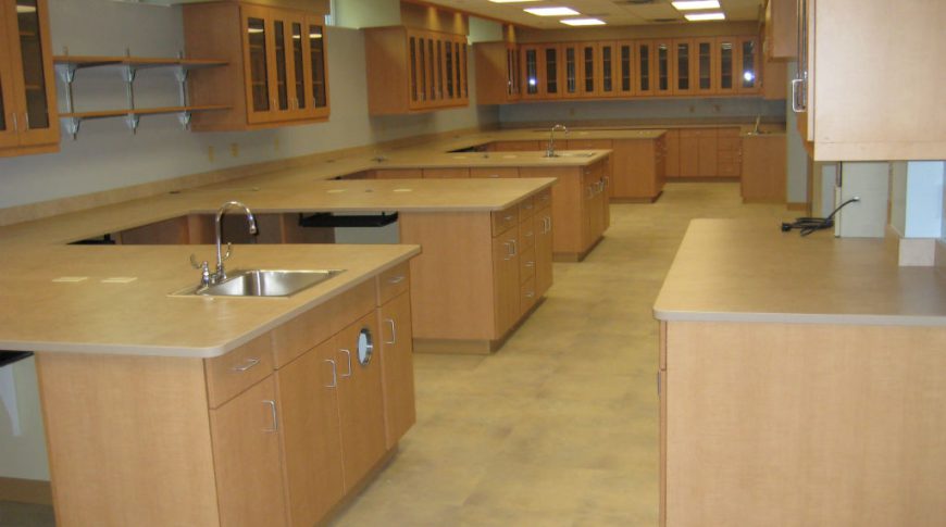 Cavalier County Memorial Hospital-Int5-1024x680-Healthcare Construction Long rectangular room with repeating sets of cabinetry and sink stations.