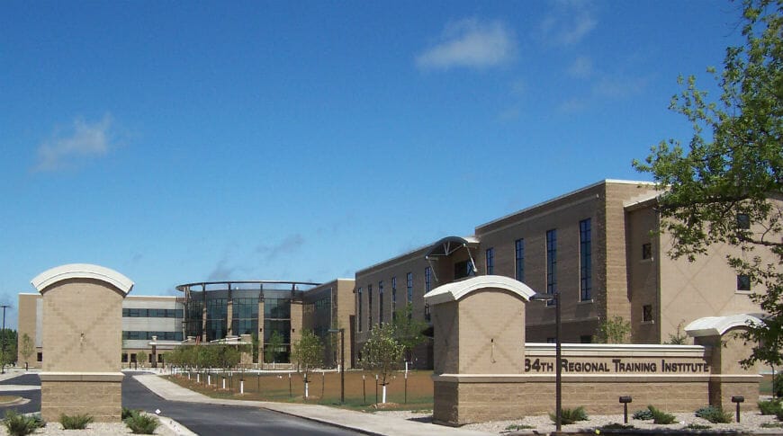 Brick-lined entryway to huge brick facility training building in the background.