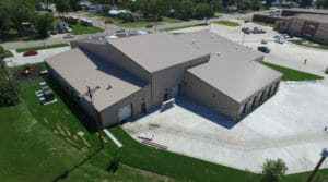 Aerial view of light concrete precast building with seven garage bays and light metal roofing.