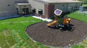 Aerial view of chain-link fenced in area of small children's playground structure.