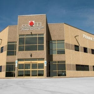 Exterior view from parking lot of Prairie Supply Inc. precast beige 2-story building.