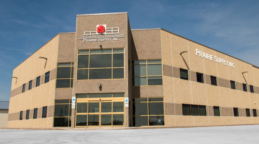 Exterior view from parking lot of Prairie Supply Inc. precast beige 2-story building.