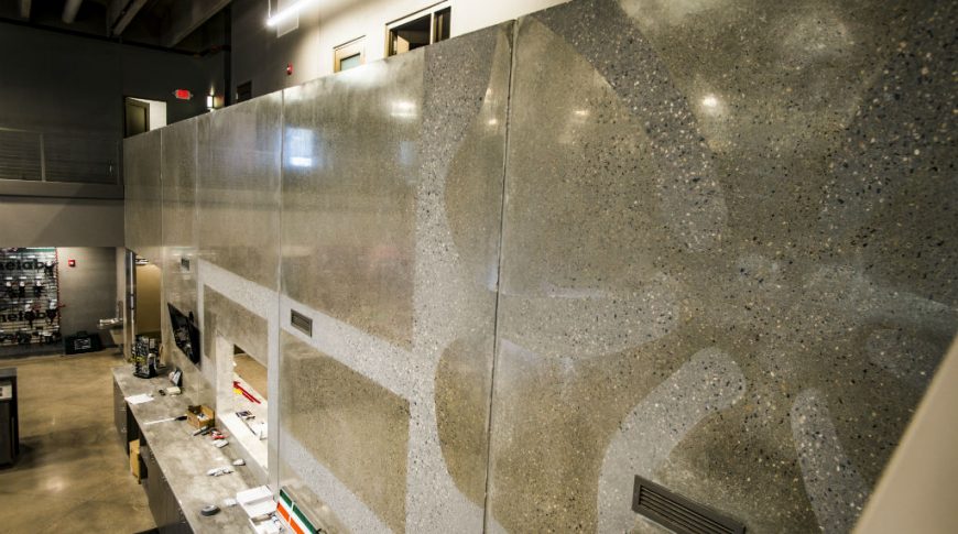 Concrete accent wall extending from second floor mezzanine railing down to first floor service countertop.