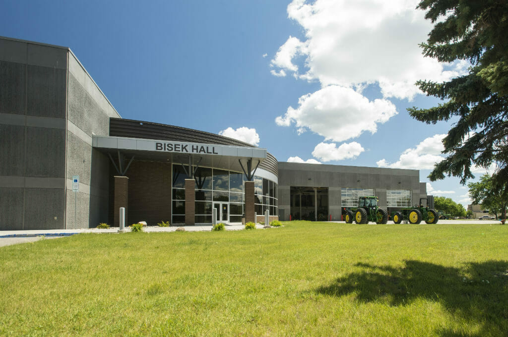 Front view of outside entrance to Bisek Hall precast concrete building with brick rotunda and floor-to-ceiling windows.