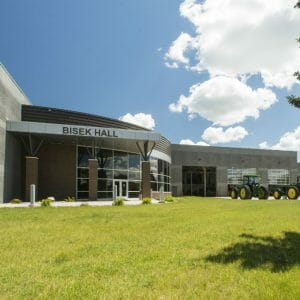 Front view of outside entrance to Bisek Hall precast concrete building with brick rotunda and floor-to-ceiling windows.
