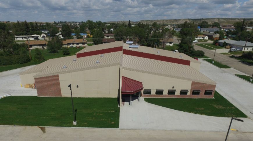 aerial view of the front of New Town Vocational School with beige concrete and red brick walls with red metal entrance roof accent and red accents throughout.