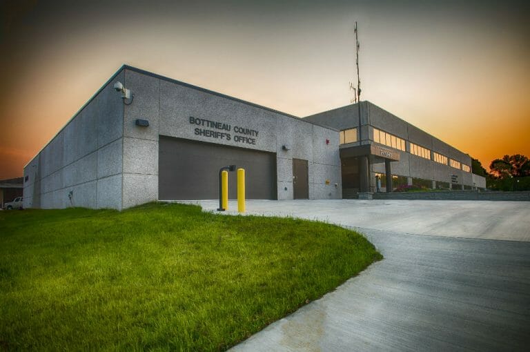 Exterior view of the Bottineau County Jail garage with concrete driveway and green grass to the front