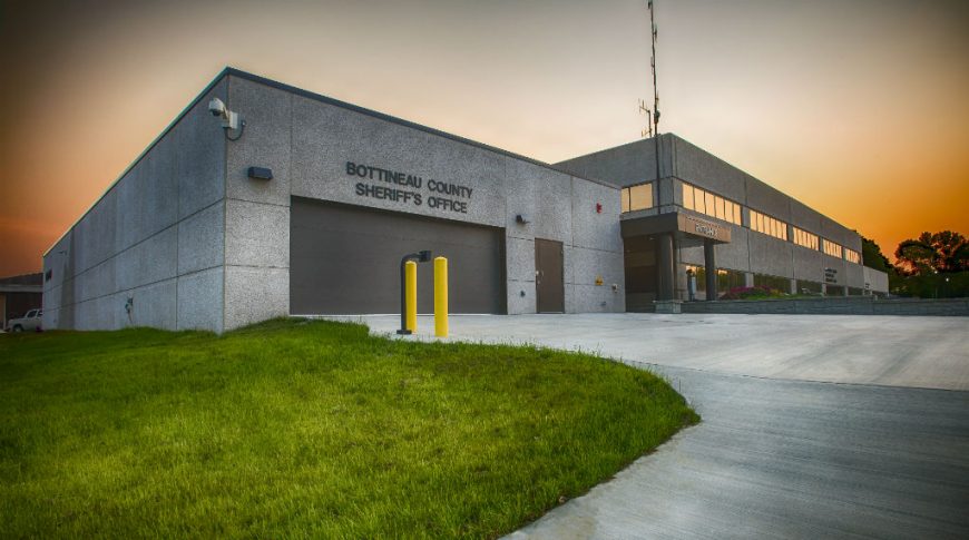 Exterior view of the Bottineau County Jail garage with concrete driveway and green grass to the front