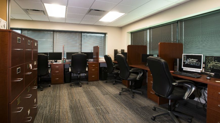 Office room full of dark cherry file cabinets and desk workstations.
