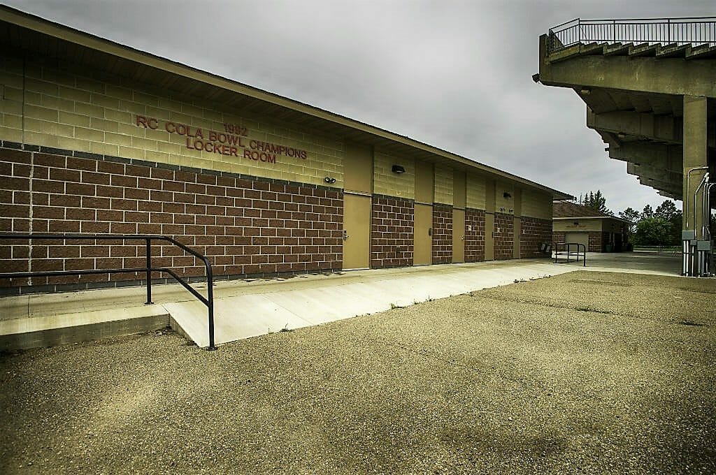 Brown brick locker room building besides concrete stadium seating