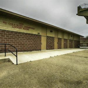 Brown brick locker room building besides concrete stadium seating