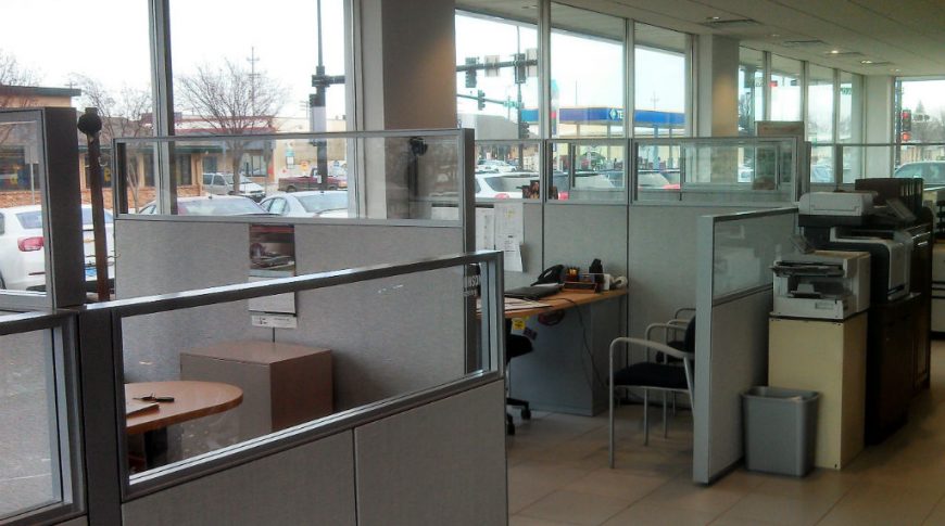 Gray office cubicles with wall of windows behind