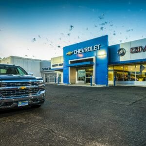 Parking lot angled view of Smith Motors gray and blue building with shiny truck to the foreground