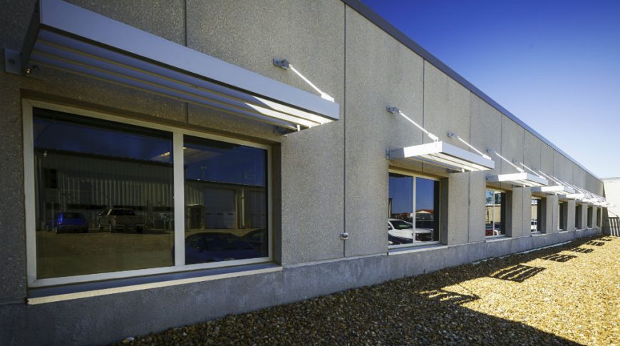 Southwest Water-P-Ext2-1024x680-Government Construction Exterior beige stucco wall with row of windows and metal awning above each