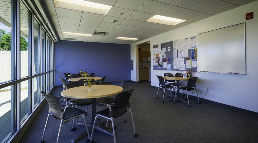 Southwest Water-P-Int3-1024x680-Government Construction Employee breakroom with dark gray speckled flooring, white nd blue accent walls and wall of windows to the left side