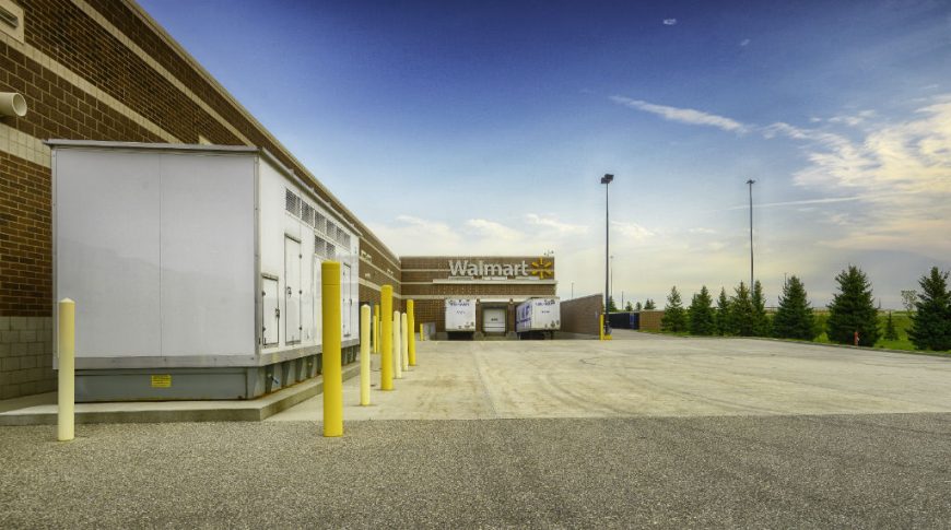 Three loading docks to brown bricked super store building with yellow bollards to the left