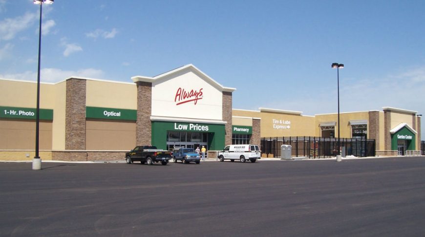 Corner parking lot view of shades of beige Walmart building with green accents throughout