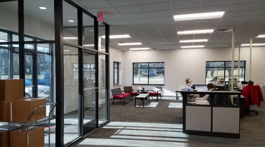 Office entryway with front desk to center and reception area to back right.