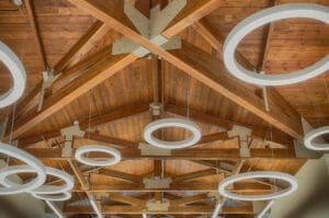 Pine stained ceiling with exposed wooden trusses and large ring lights