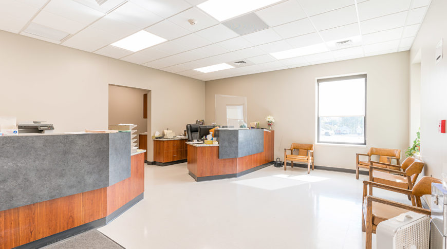 Administration offices with two tall wooden desks with offices behind and chairs in entrance