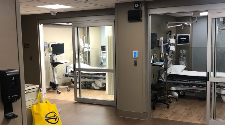 Hallway looking towards two emergency rooms with sliding full-glass doors.