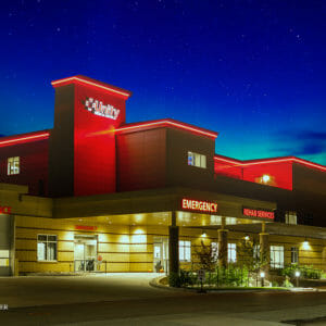 Night snapshot of the outside of the Unity Medical Center building showcasing neon lit signs for the Emergency, Ambulance, and Rehab Services entrances.