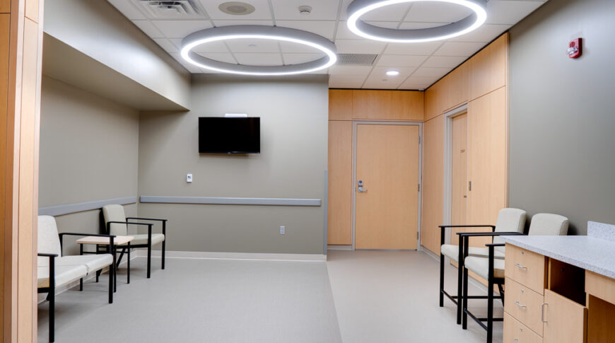 Waiting room with four tables, oak cabinetry and paneling and three circular lights on the ceiling.