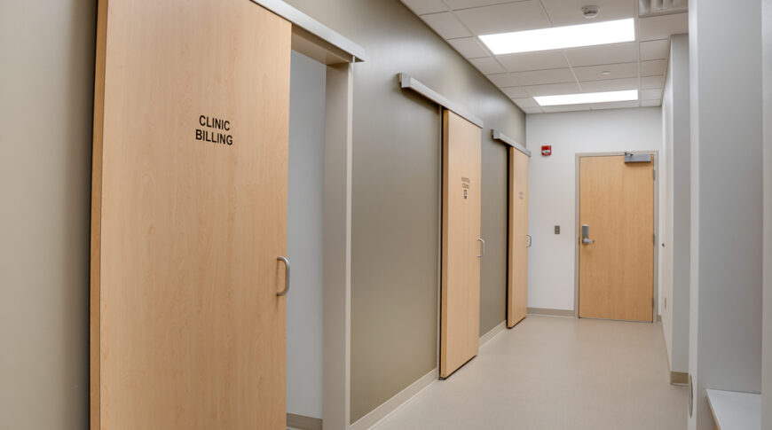 Hallway behind exam rooms with white oak sliding barn doors.