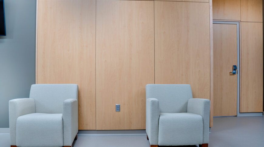 Waiting area with white oak paneling and two light blue sitting chairs.