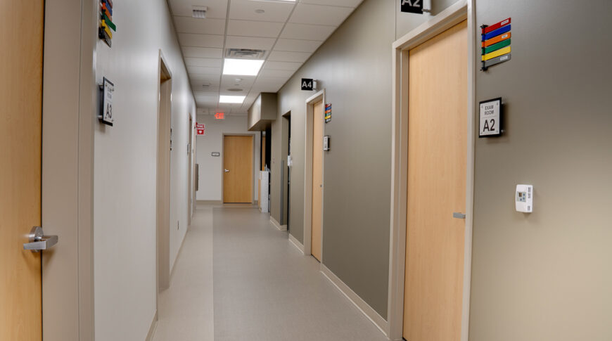 Hallway with white oak doors lining the halls with numbered rooms and colored labels outside the doors.