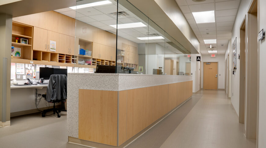 Nurses station with white oak cabinetry and glass divider.