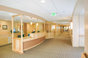 Entry reception desk with light maple wood and rippled glass accents throughout.