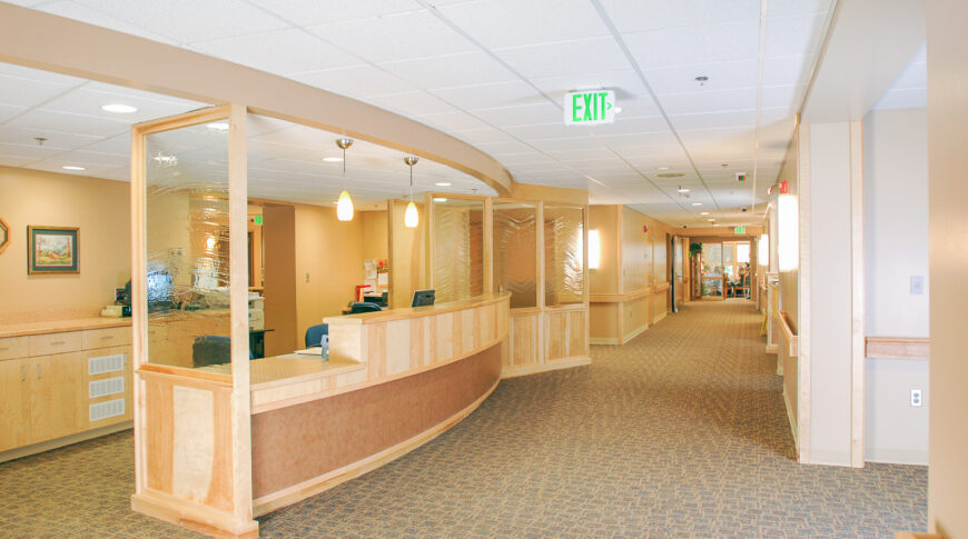 Entry reception desk with light maple wood and rippled glass accents throughout.