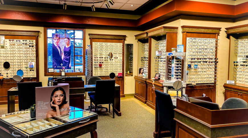 Eye glass retail store section of InVision Eye Clinic with built-in cabinetry holding glasses on the walls and fitting tables throughout the foreground.