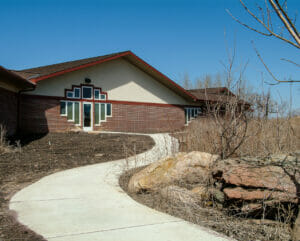 Exterior entrance to red bricked building with unique geometric window pattern flanking each side of the door and above it.